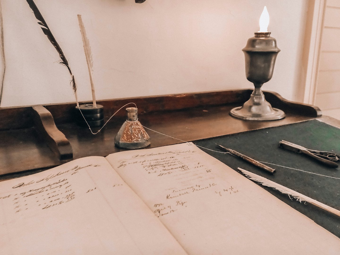 Antieke schrijftafel met kasboek, ganzenveerpennen en olielamp.